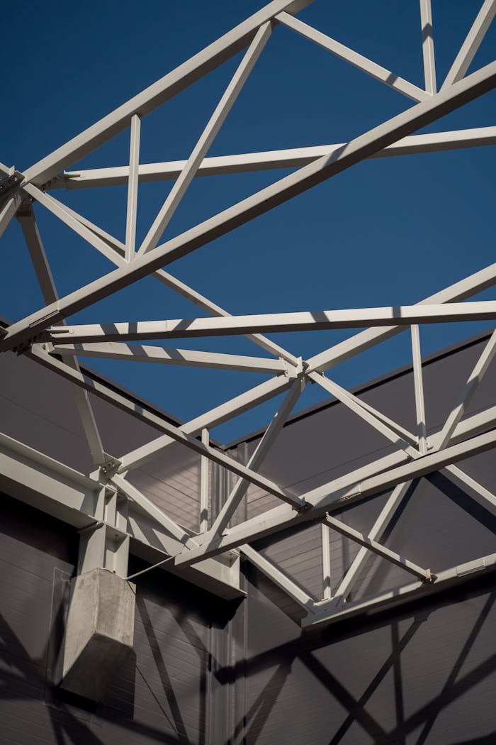 Steel beams form an intricate lattice against a clear blue sky in this industrial architecture shot.